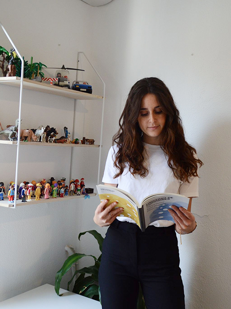 Laura de pie leyendo un libro